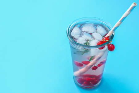 Glass of fresh mojito cocktail with red currant on color backgroundの写真素材