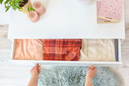 Woman folding clothes in chest of drawersの写真素材