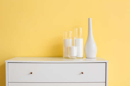 Modern chest of drawers with candles near color wall in roomの写真素材