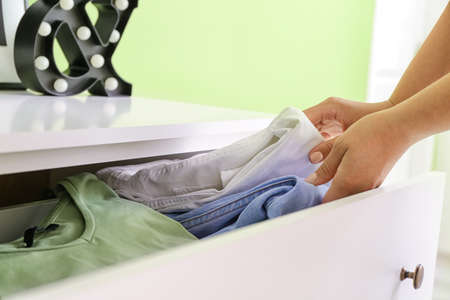 Woman folding clothes in chest of drawersの写真素材