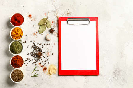 Spices and blank clipboard on white table