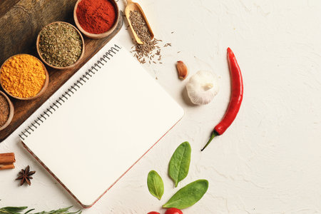 Notebook for recipes and spices on white tableの写真素材