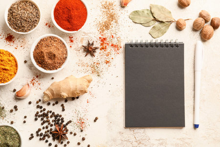 Black notebook and set of spices on white tableの写真素材