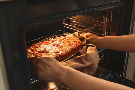 Woman taking baking dish with tasty rice casserole out of ovenの写真素材
