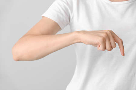 Young deaf mute woman using sign language on gray background, closeup