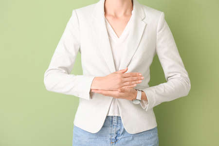 Young deaf mute woman using sign language on color backgroundの写真素材