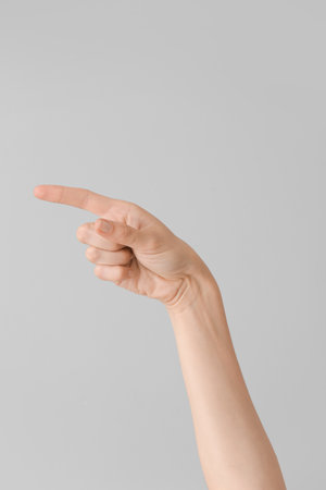 Hand showing letter G on gray background. Sign language alphabetの写真素材