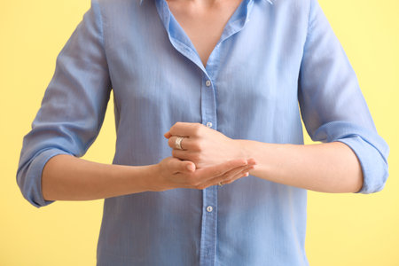 Young deaf mute woman using sign language on color backgroundの写真素材