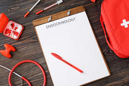 Clipboard with word ENDOCRINOLOGY, thyroid gland, syringes, stethoscope and pills on wooden backgroundの写真素材