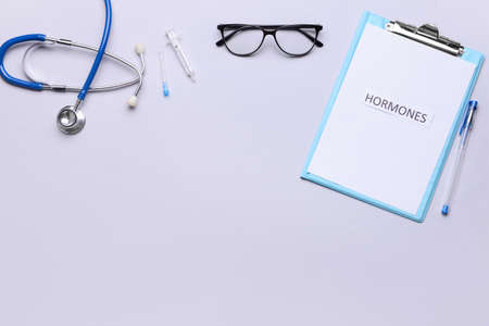 Clipboard with word HORMONES, stethoscope and eyeglasses on gray backgroundの写真素材