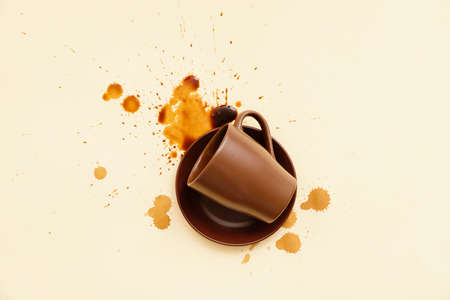Overturned cup and spilled coffee on color backgroundの写真素材