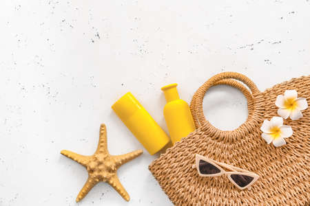 Beach bag with sunscreen cream and sunglasses on white background