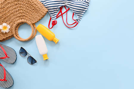 Beach bag with sunscreen cream and accessories on color background