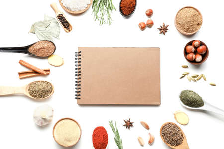 Empty notebook among various spices on white background