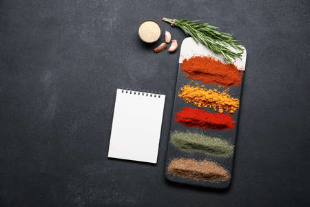 Empty notebook with various spices on dark backgroundの写真素材