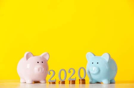 Piggy banks with savings and figure 2020 on color background. Concept of pensionの写真素材