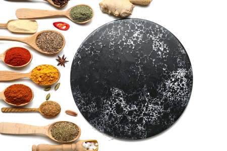Dark board among various spices on white backgroundの写真素材