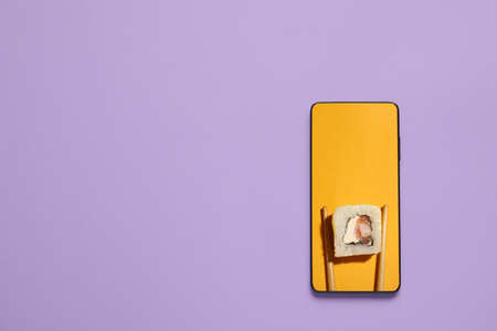 Tasty sushi roll on screen of mobile phone on color background