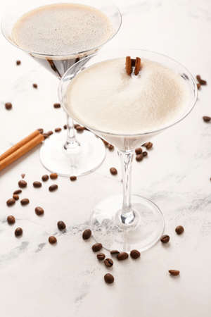 Glasses of coffee martini on light background