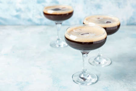 Glasses of coffee martini on color background