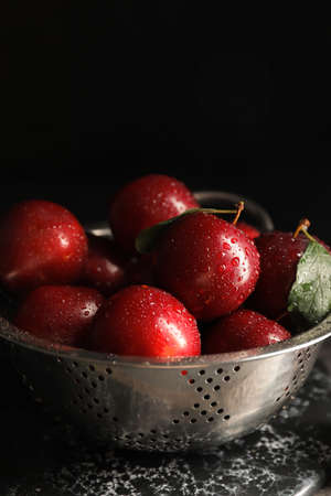 Colander with ripe fresh plums on dark backgroundの写真素材