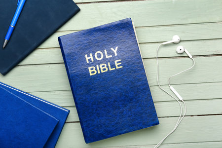Holy Bible and earphones on wooden table