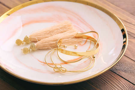 Plate with golden jewelry on wooden backgroundの写真素材