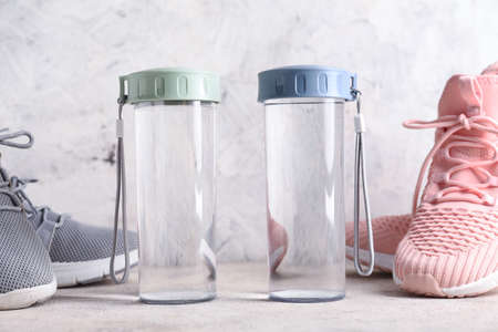 Bottle of clean water with shoes on light backgroundの写真素材