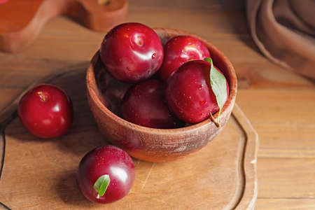 Bowl with fresh ripe plums on wooden tableの写真素材