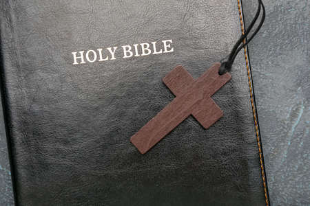 Holy Bible and cross on dark background