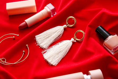 Beautiful composition with jewelry and decorative cosmetics on color clothの写真素材