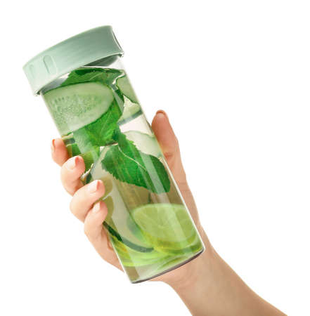 Hand with bottle of clean water with cucumber and lime on white backgroundの写真素材