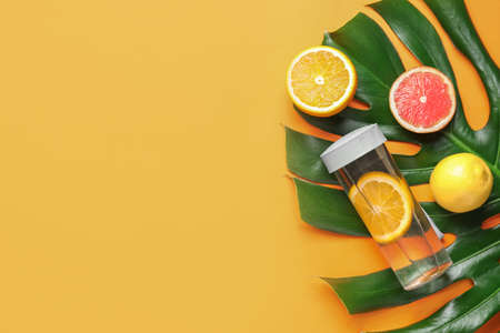 Bottle of clean water with citrus on color backgroundの写真素材