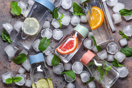 Bottles of clean water with citrus, ice cubes and mint as backgroundの写真素材