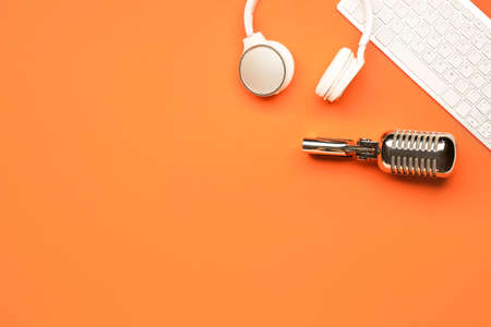 Headphones with microphone and computer keyboard on color background