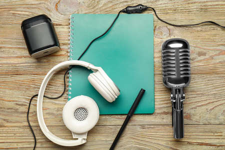 Headphones with microphone, notebook and speaker on wooden backgroundの写真素材