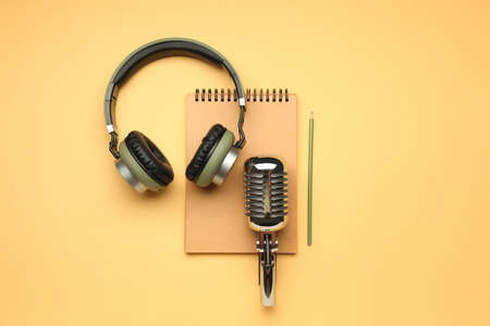 Headphones with microphone and notebook on color backgroundの写真素材