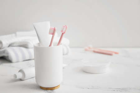 Holder with toothbrushes and paste on table in bathroomの写真素材