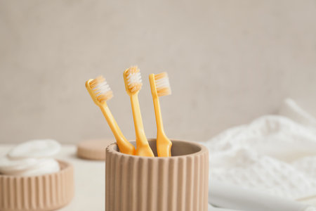 Holder with toothbrushes on table in bathroomの写真素材