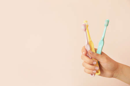 Female hand with different toothbrushes on color backgroundの写真素材