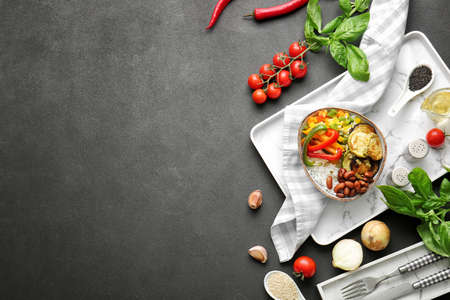 Plate of delicious rice salad with vegetables on black background