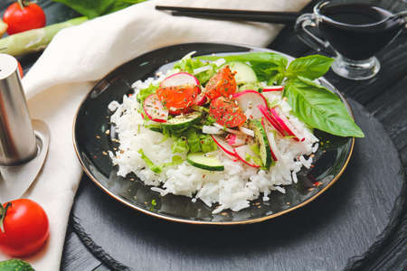 Plate of delicious rice salad with vegetables on dark wooden backgroundの写真素材