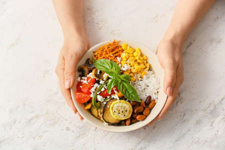 Woman with rice salad on light backgroundの写真素材
