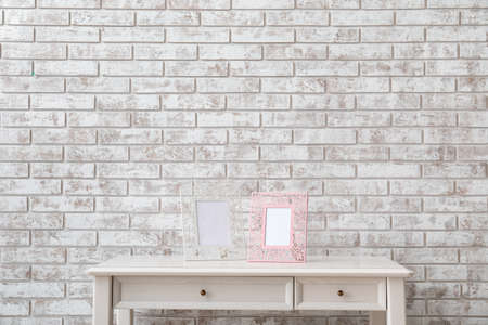 Blank photo frames on table near brick wall