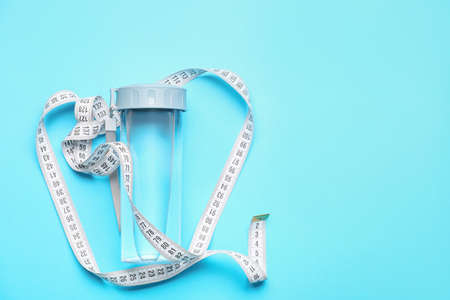 Bottle of water and measuring tape on color background