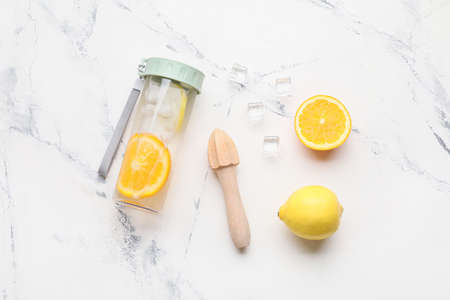 Bottle of infused water with citruses on light background