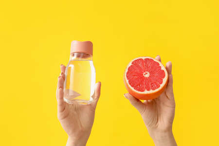 Female hands, bottle of water and grapefruit on color backgroundの写真素材