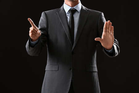 Young businessman using virtual screen on dark backgroundの写真素材