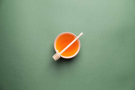 Bowl with honey on color background