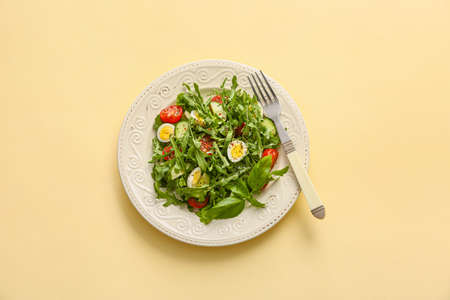 Plate with tasty arugula salad on color background